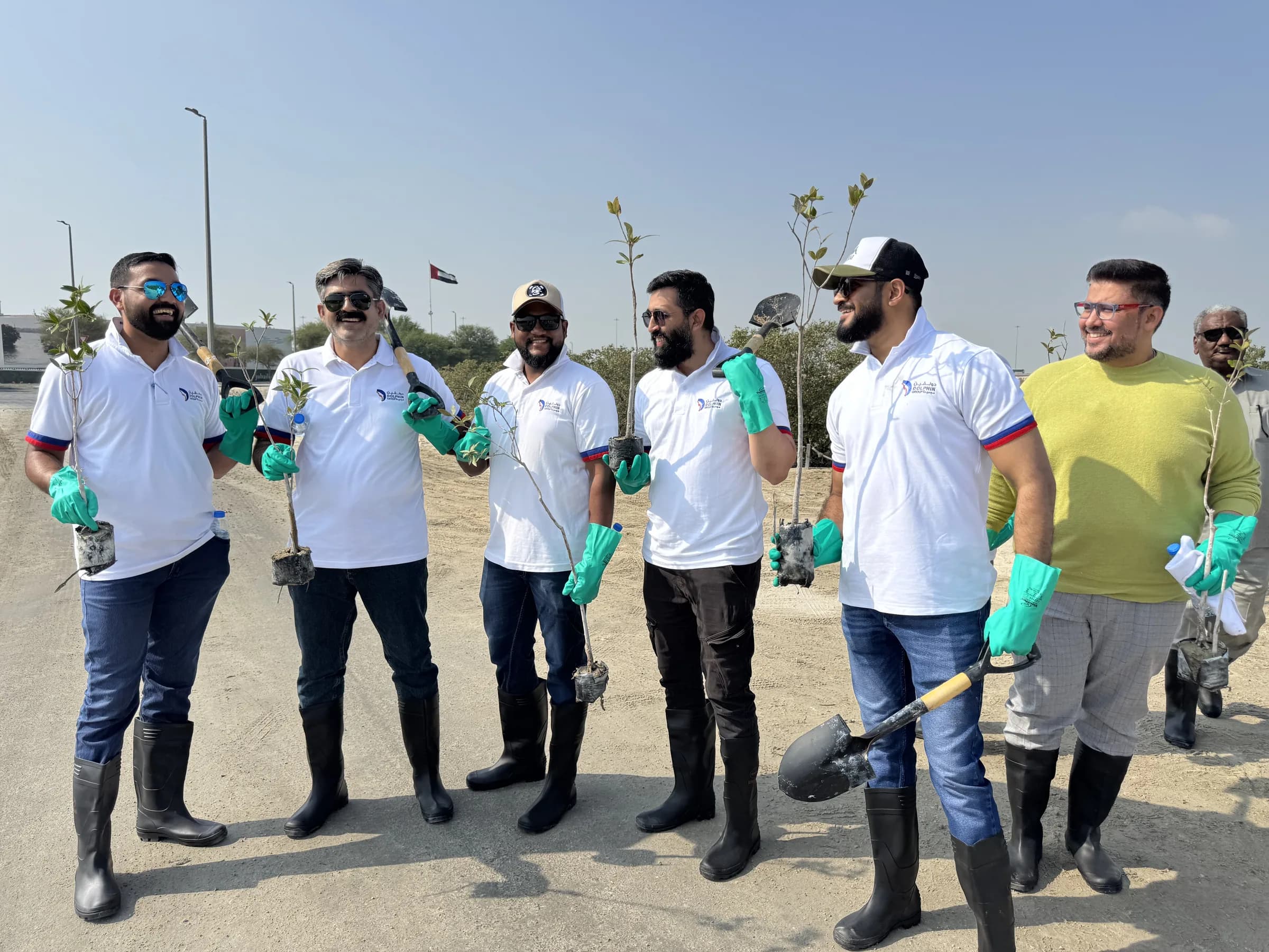 Dolphin Group team members holding mangrove seedlings and shovels before a planting drive