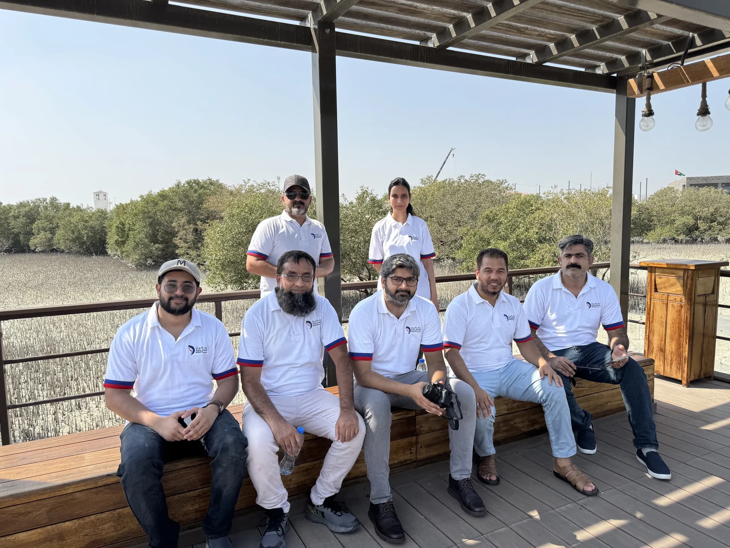 Dolphin Group team members resting on a boardwalk beside the mangrove forest